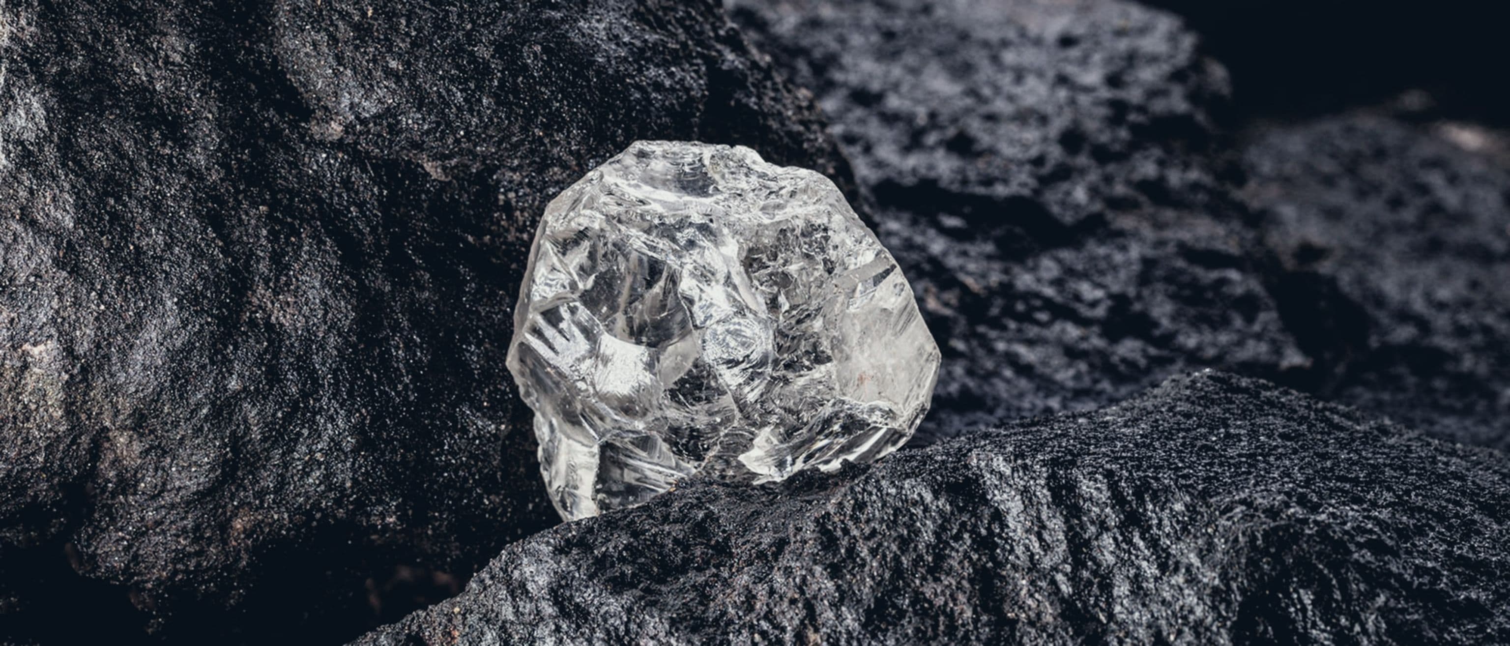 Natural rough diamond resting against dark rock